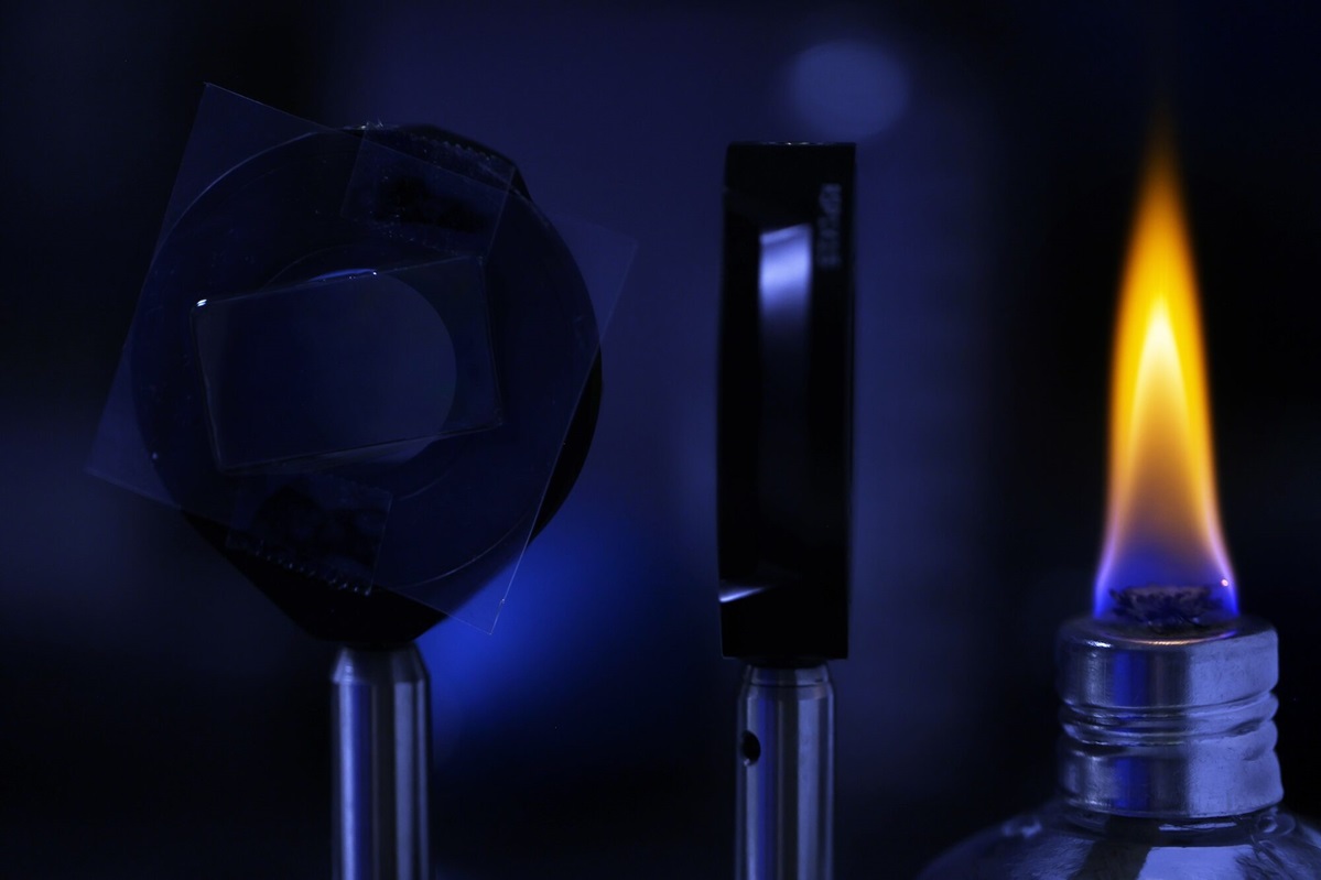 To measure how well the film twists light at high temperatures, U-M researchers use a small flame as a light and heat source.