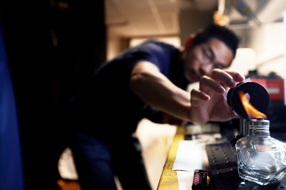 Jun Lu, an adjunct research investigator working in Kotov’s lab and the study’s first author, demonstrates how he uses a fire to test a film’s ability to twist light at high temperatures.